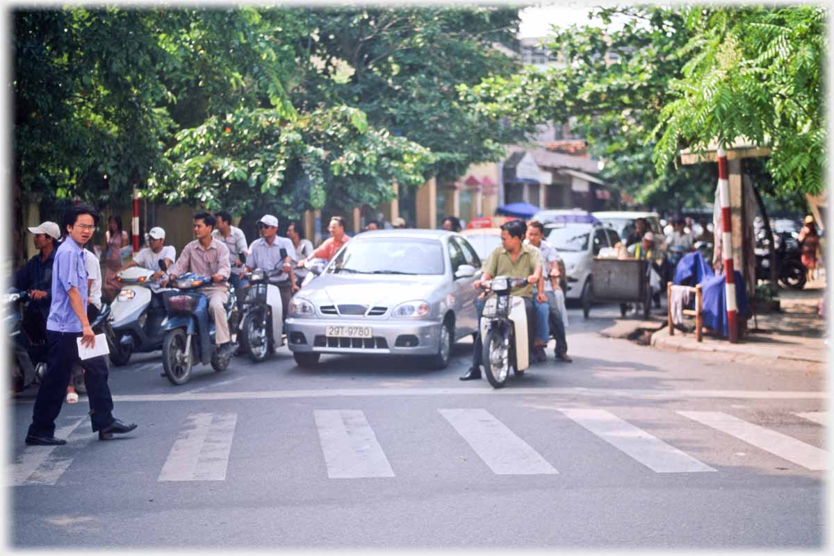 Man setting out on crossing with many vehicles waiting for him.