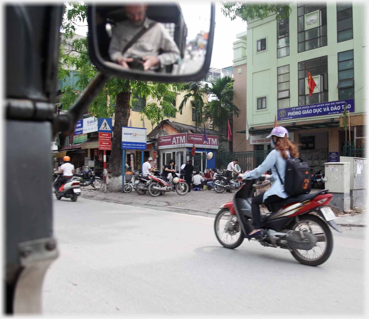 Woman on motorbike, car mirror showing reflection of me with camera.