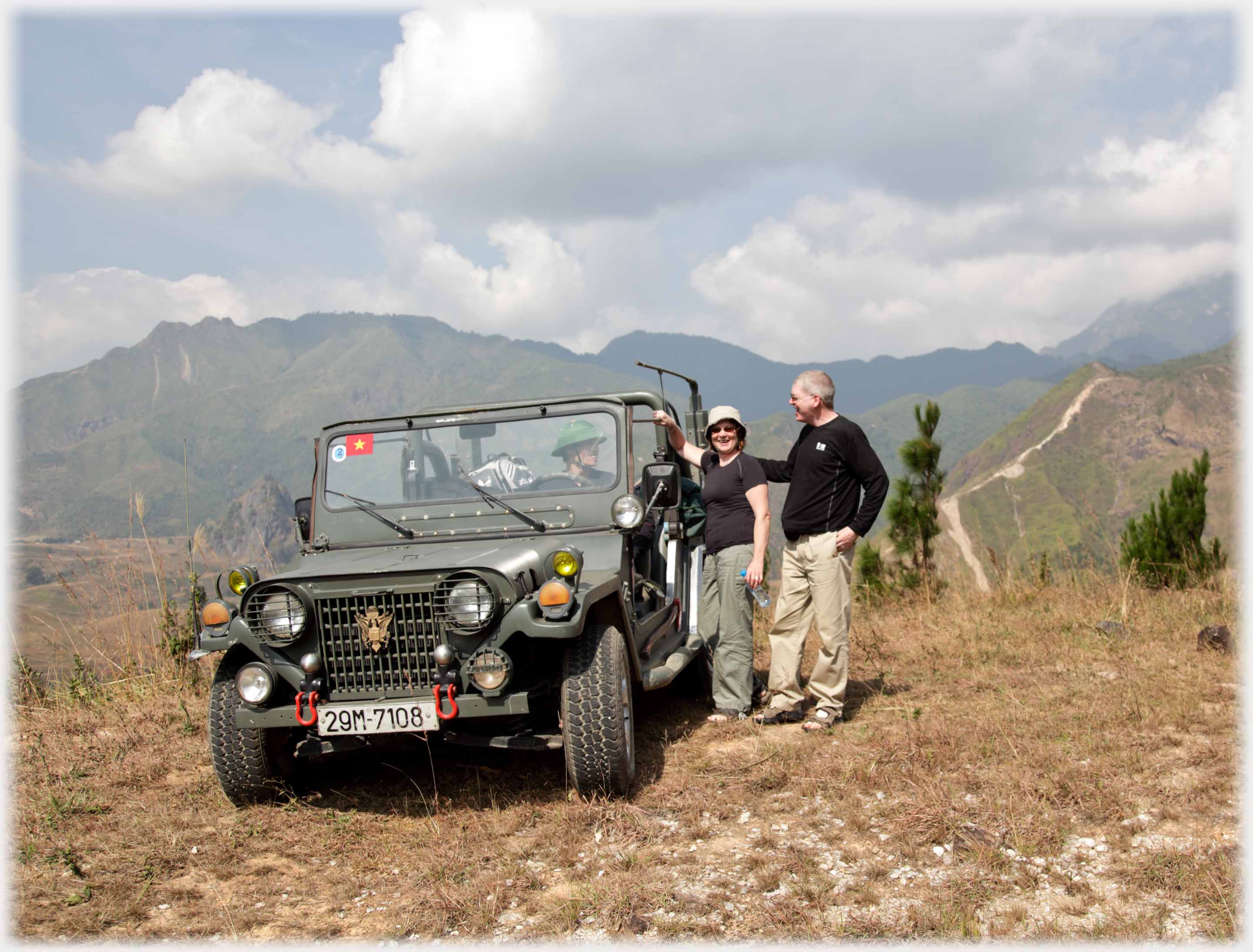 Jeep parked on rough ground man and woman standing beside it.