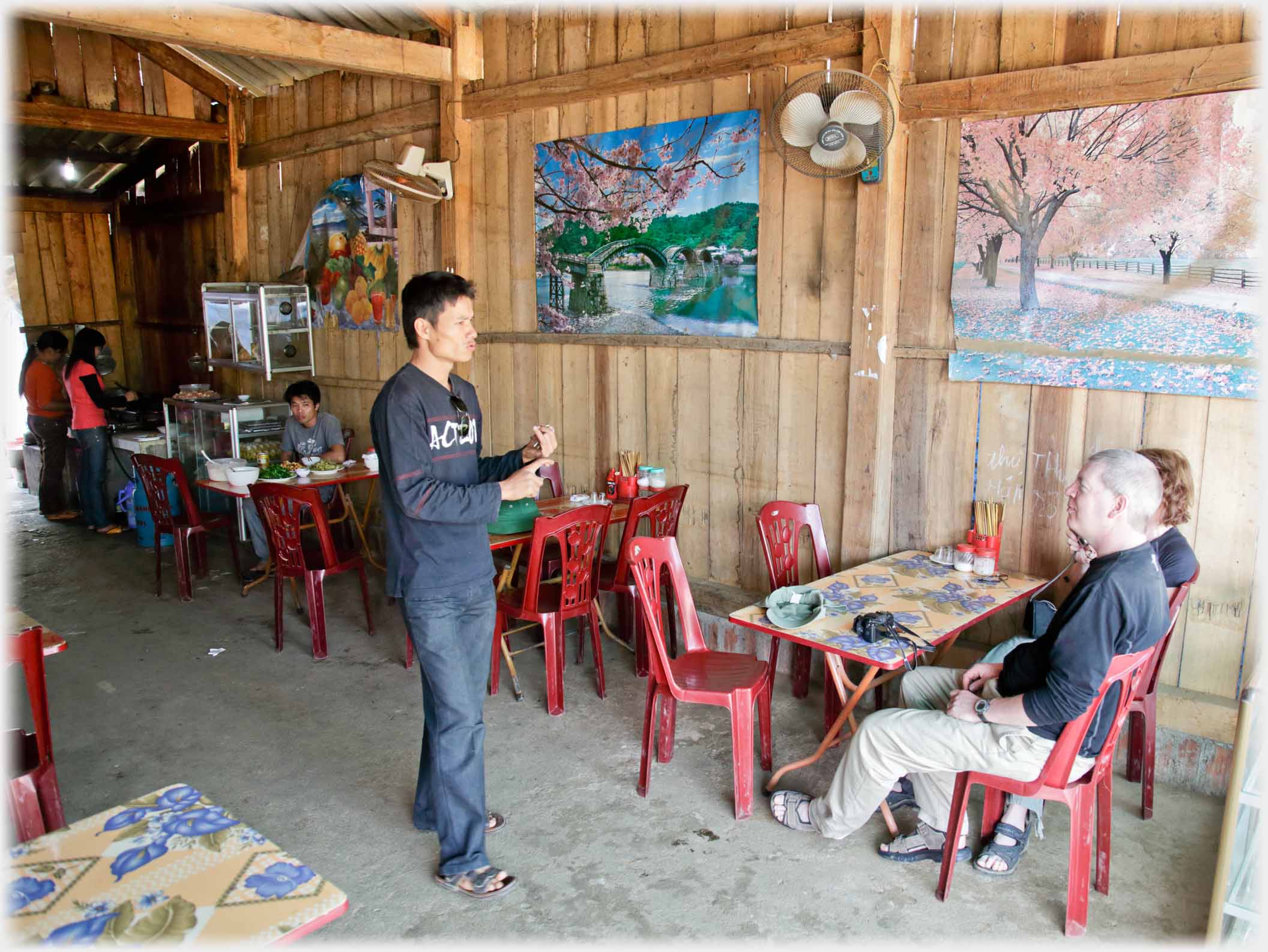 Han standing by a table with two people sitting, counting off on his fingers.