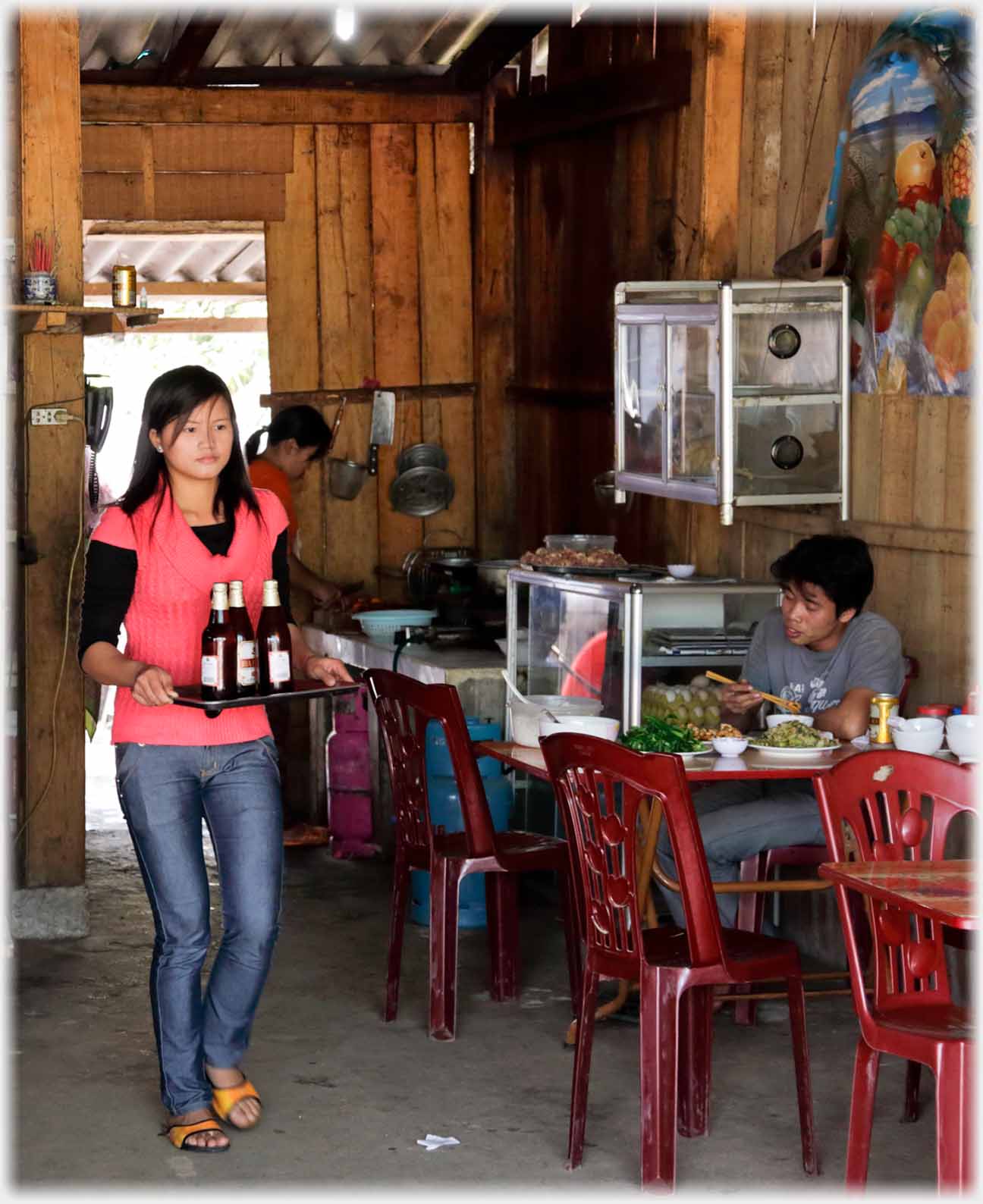 Girl walking with three beers on a tray.