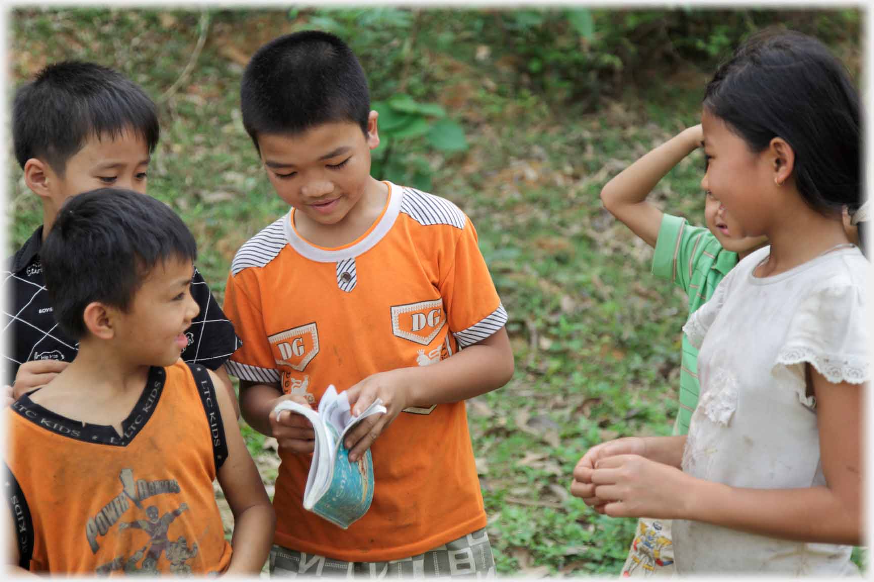 Boy opening book while others watch.