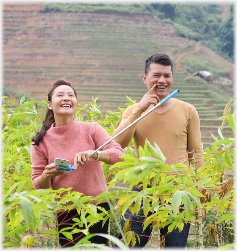 Man and woman laughing amongst plants.