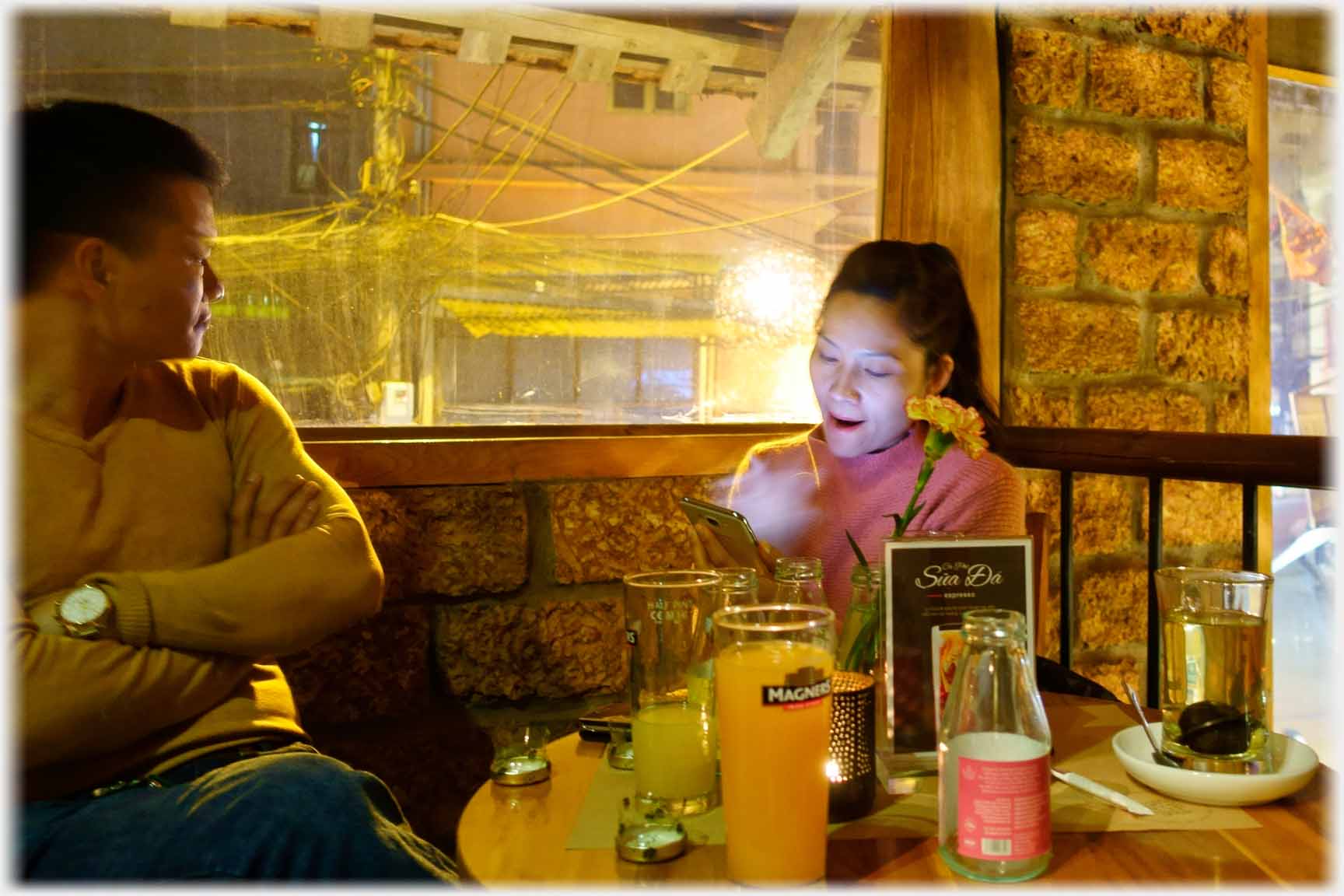 Woman looking at phone beside table, man looking out window