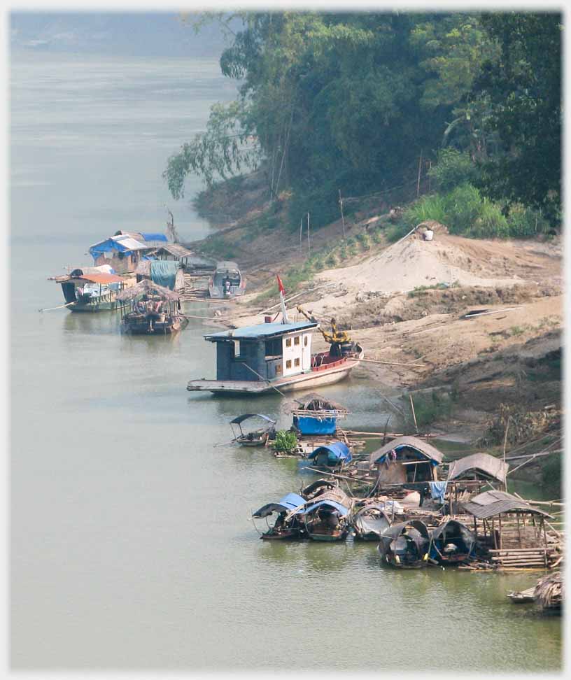 Group of houseboats at river bank.