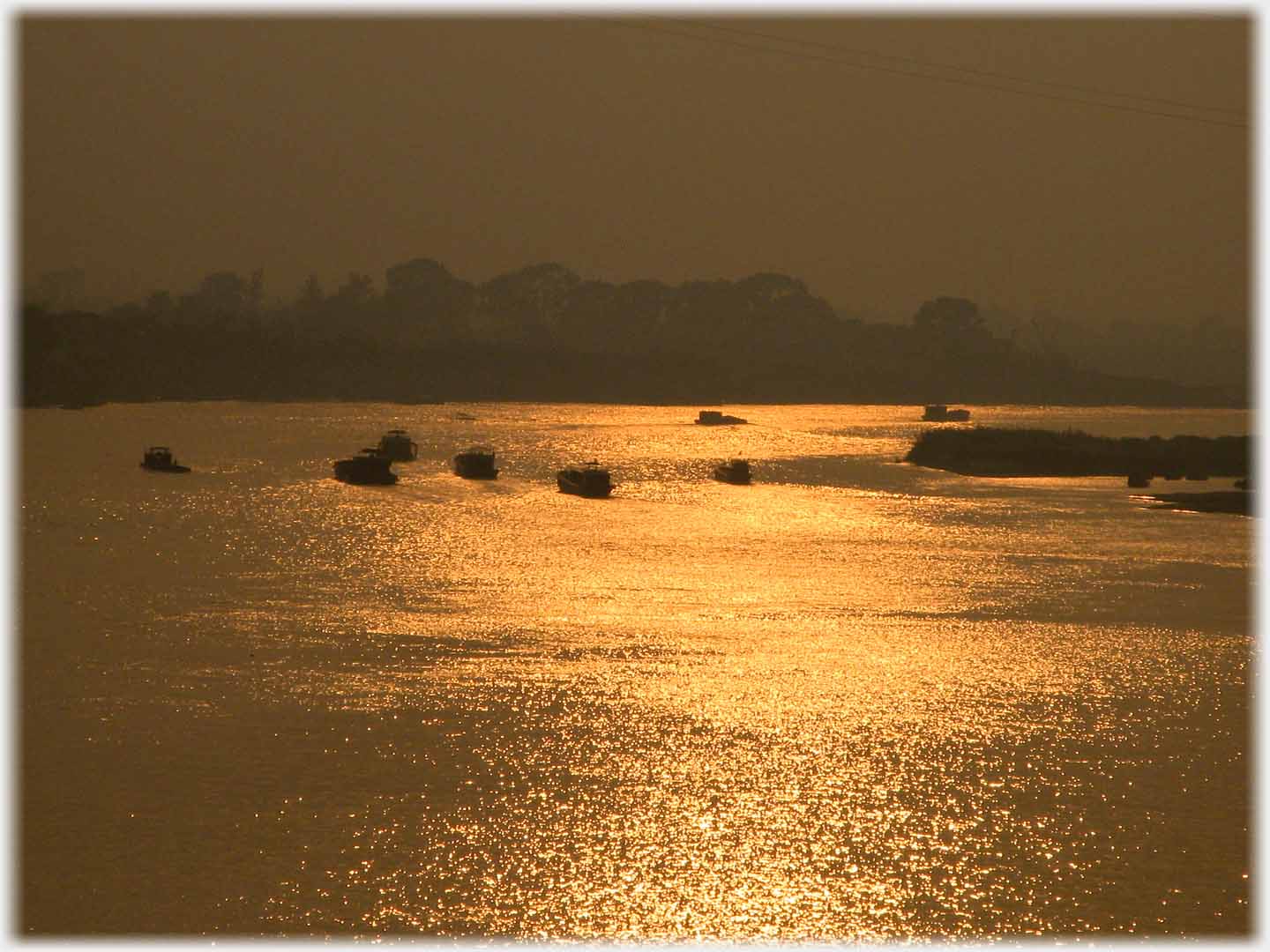 Longer distance shot of sun reflection with silhouettes of many boats.