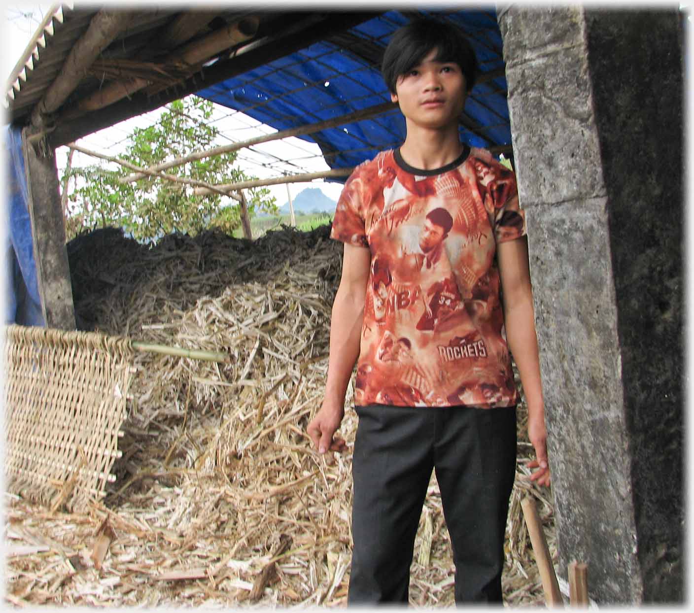 One of the workers looking at photographer, wearing bright complex tee-shirt.