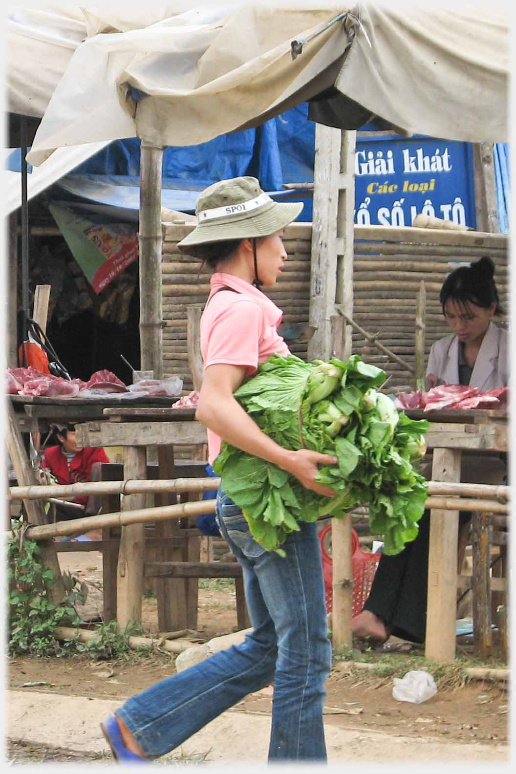 Womman carrying large bundle of greens.