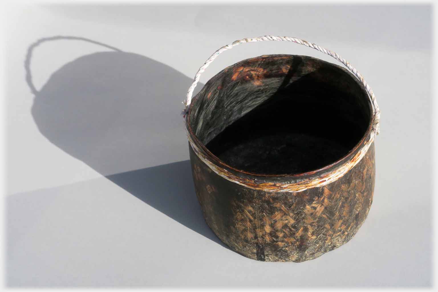 Small pot with string handle.